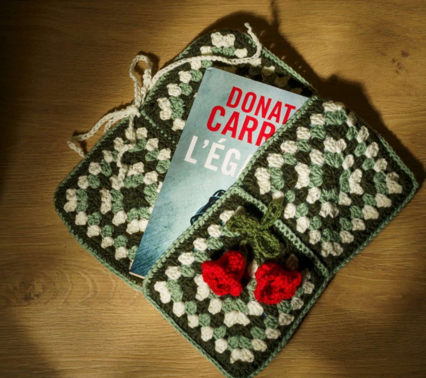 Sac en crochet et livre posés sur un parquet, lumière rasante