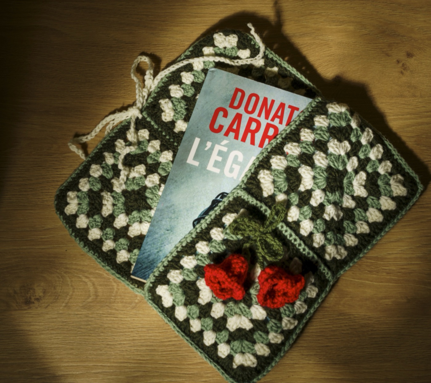 Sac en crochet et livre posés sur un parquet, lumière rasante