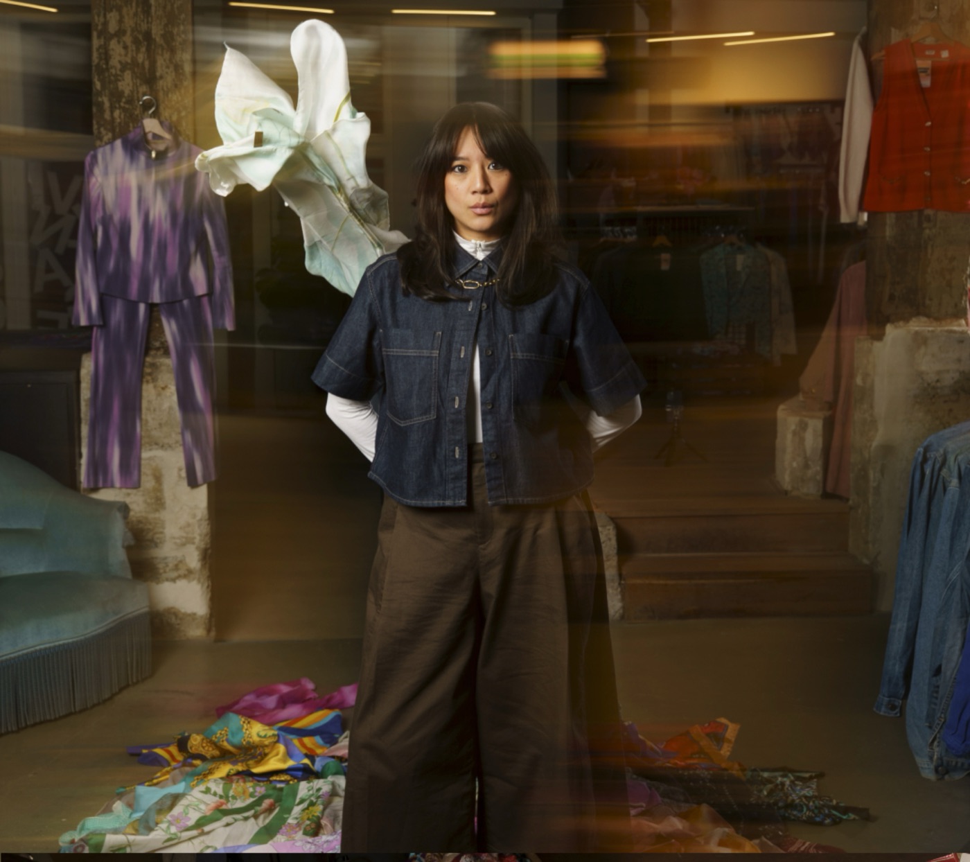 Shooting mode dans une boutique vintage : mannequin en veste denim au milieu des portants